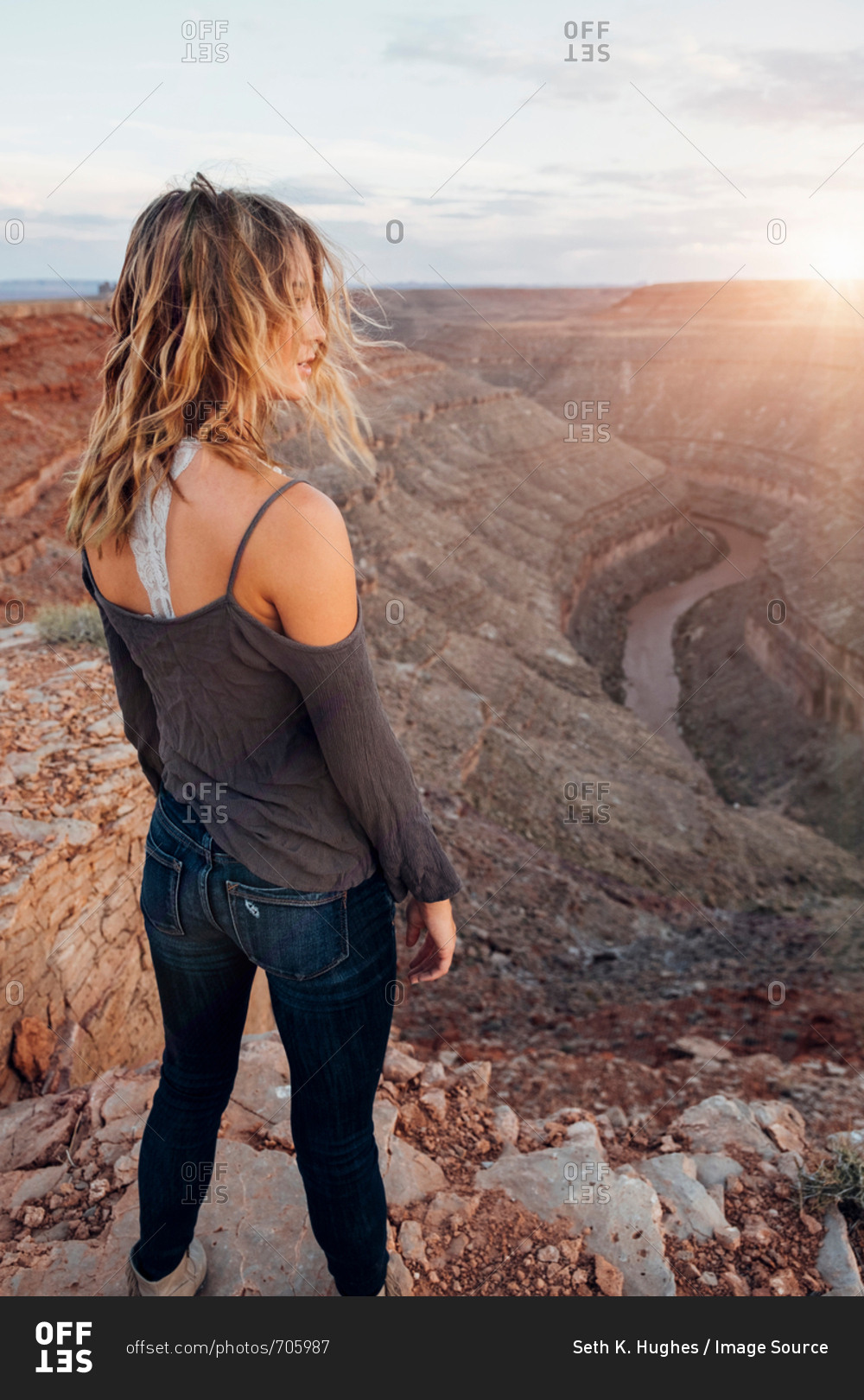 Young woman in remote setting, standing on cliff edge, looking at view, rear view, Mexican Hat, Utah, USA