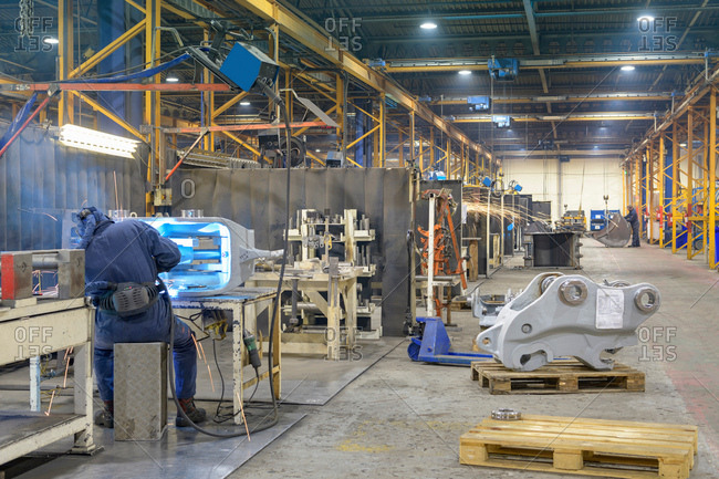Wide angle view of engineering factory with welder working in foreground