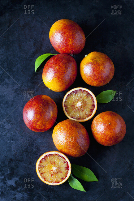 Whole and sliced blood oranges on dark ground