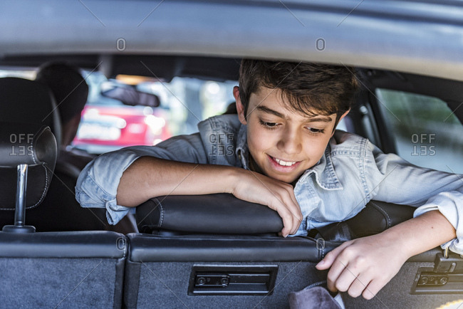 Smiling boy in car looking in boot