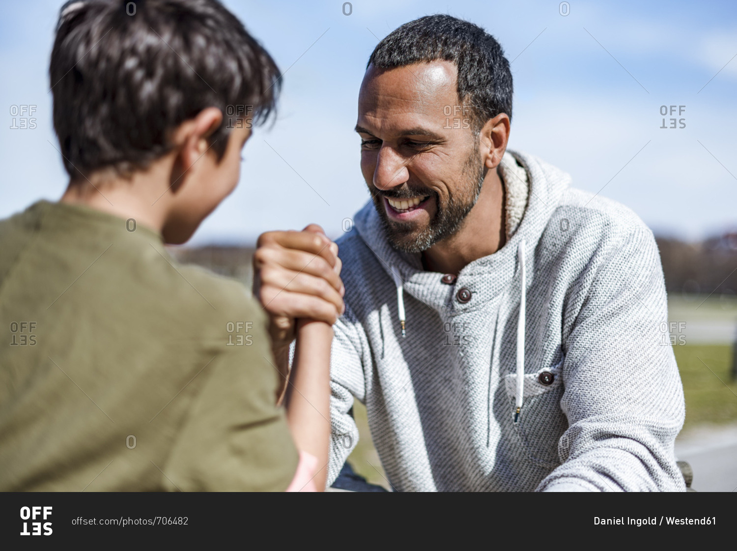 Father and son arm wrestling outdoors