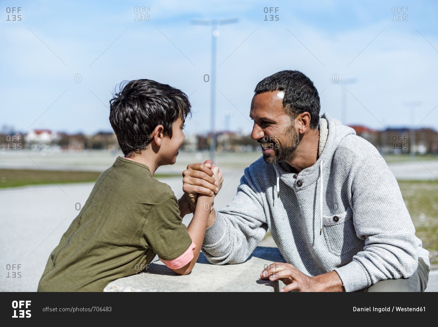 Father and son arm wrestling outdoors