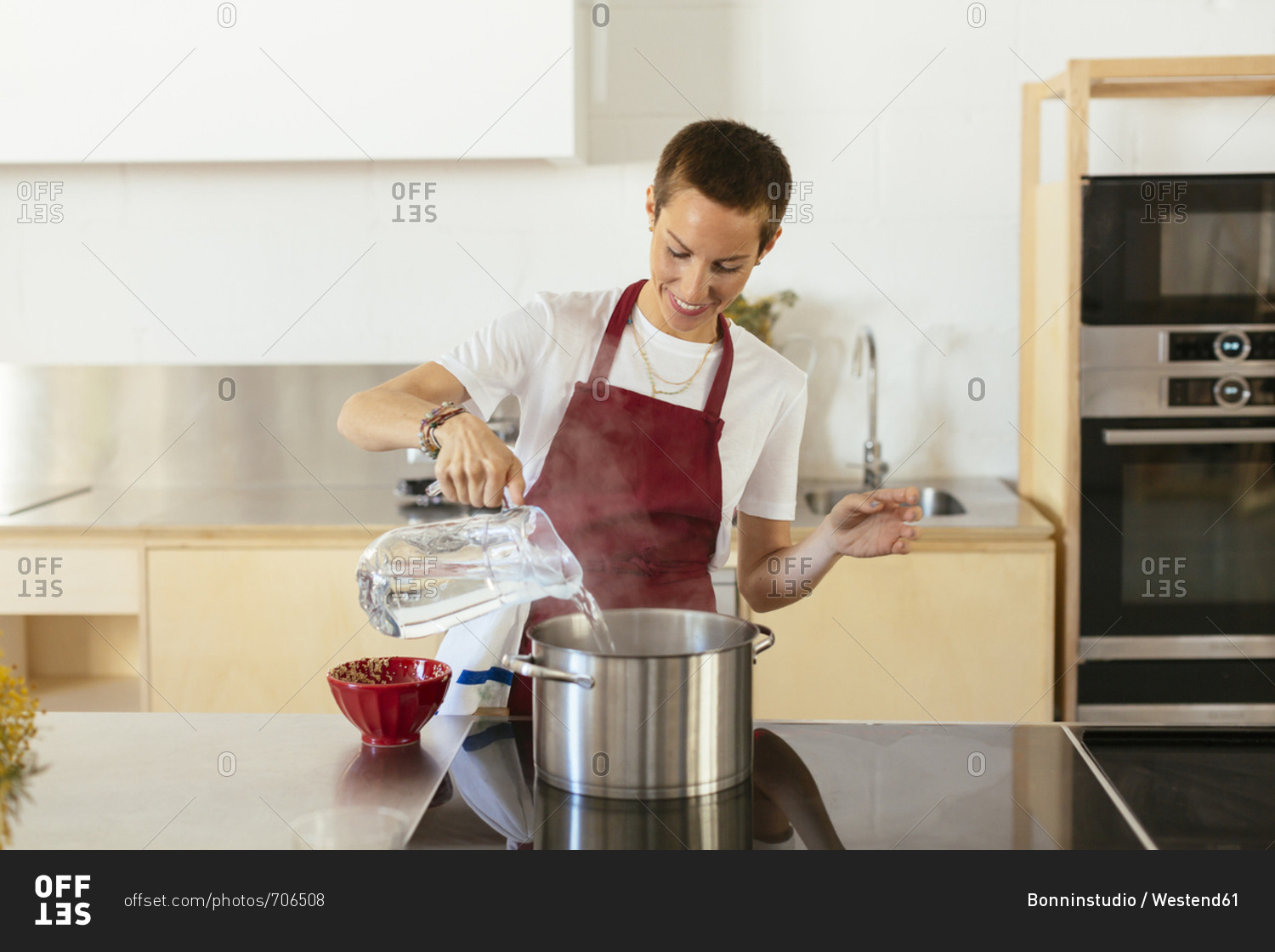 Woman boiling water in cooking pot in kitchen stock photo OFFSET