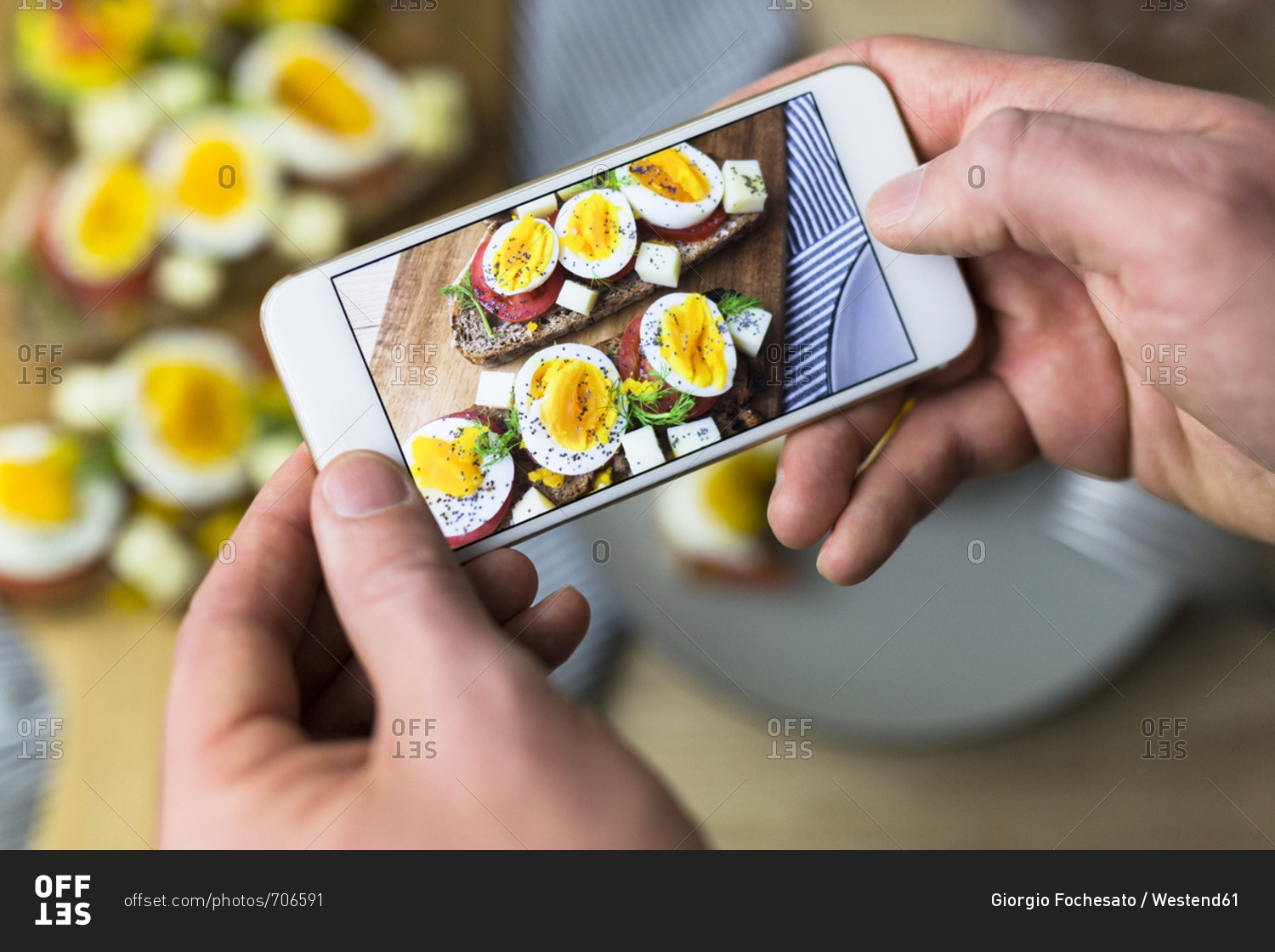 Man holding smartphone with photo of vegetarian breakfast with bread and eggs