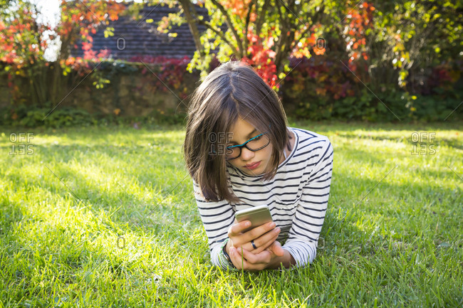 Girl lying on meadow using smartphone