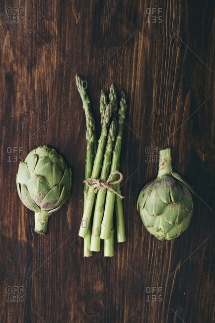 Asparagus and artichokes on a wood table tied with twine