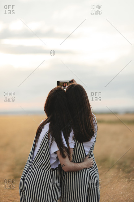 Rearview of two women wearing matching outfits taking a selfie