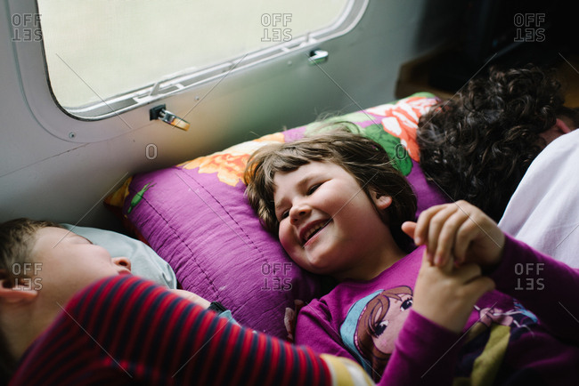 Kids lying beside father in camper laughing