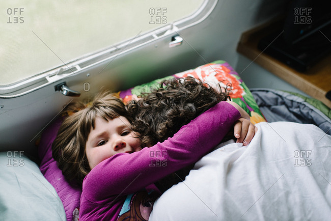 Girl hugging father in camper bed