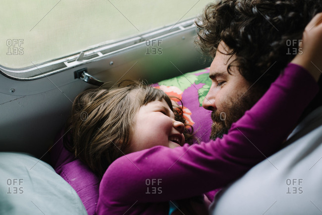 Girl waking father up with a hug in camper bed