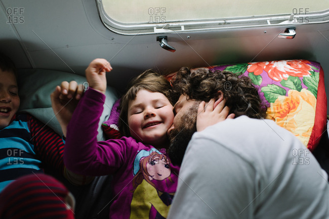 Kids lying beside father in camper bed