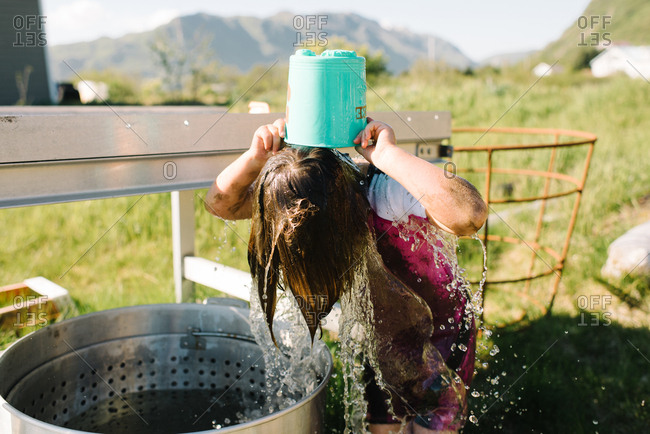 Little girl dumping a bucket of water over her head