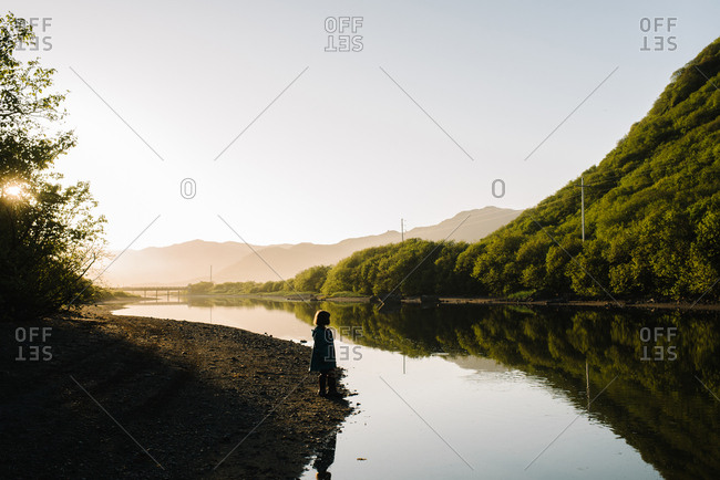 Silhouette of young girl on a riverbank in Alaska at sunset
