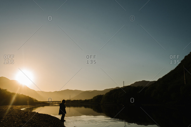 Young girl stepping into a river in Alaska at sunset