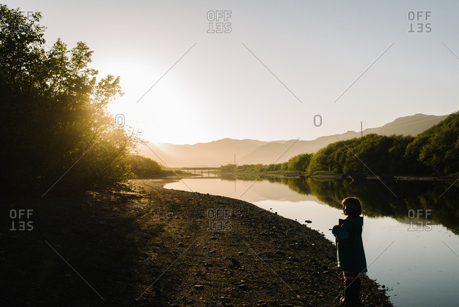 Young girl splashing in a riverbank in Alaska at sunset