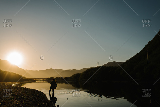 Young girl walking in a river in Alaska at sunset