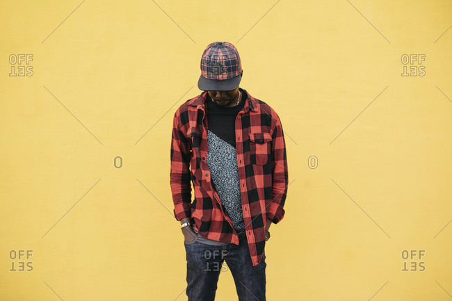 African man with cap posing on a yellow background, wearing casual clothing