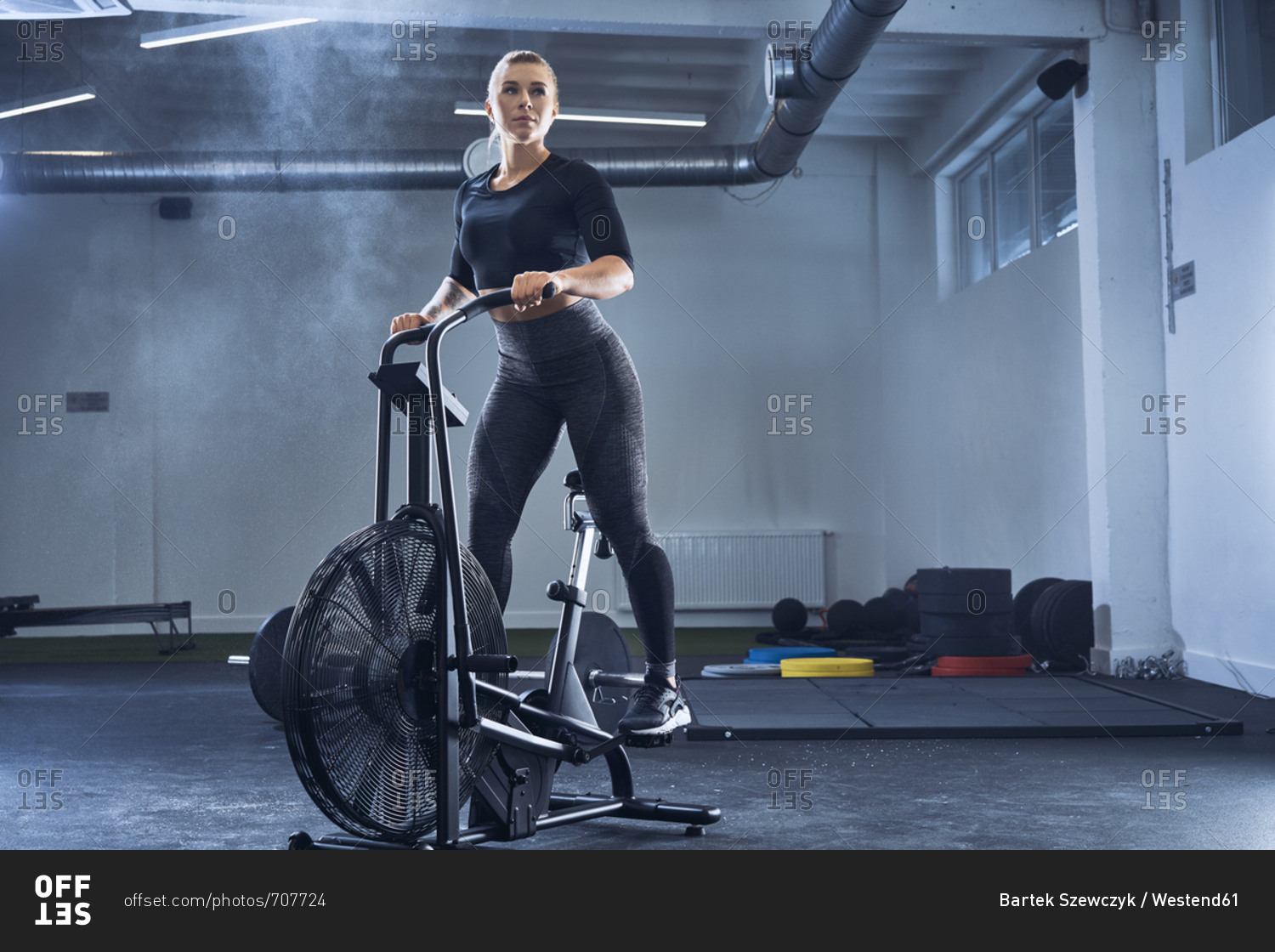 Athletic woman doing air bike workout at gym