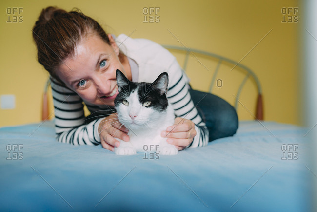 Happy woman with a black and white cat on the bed