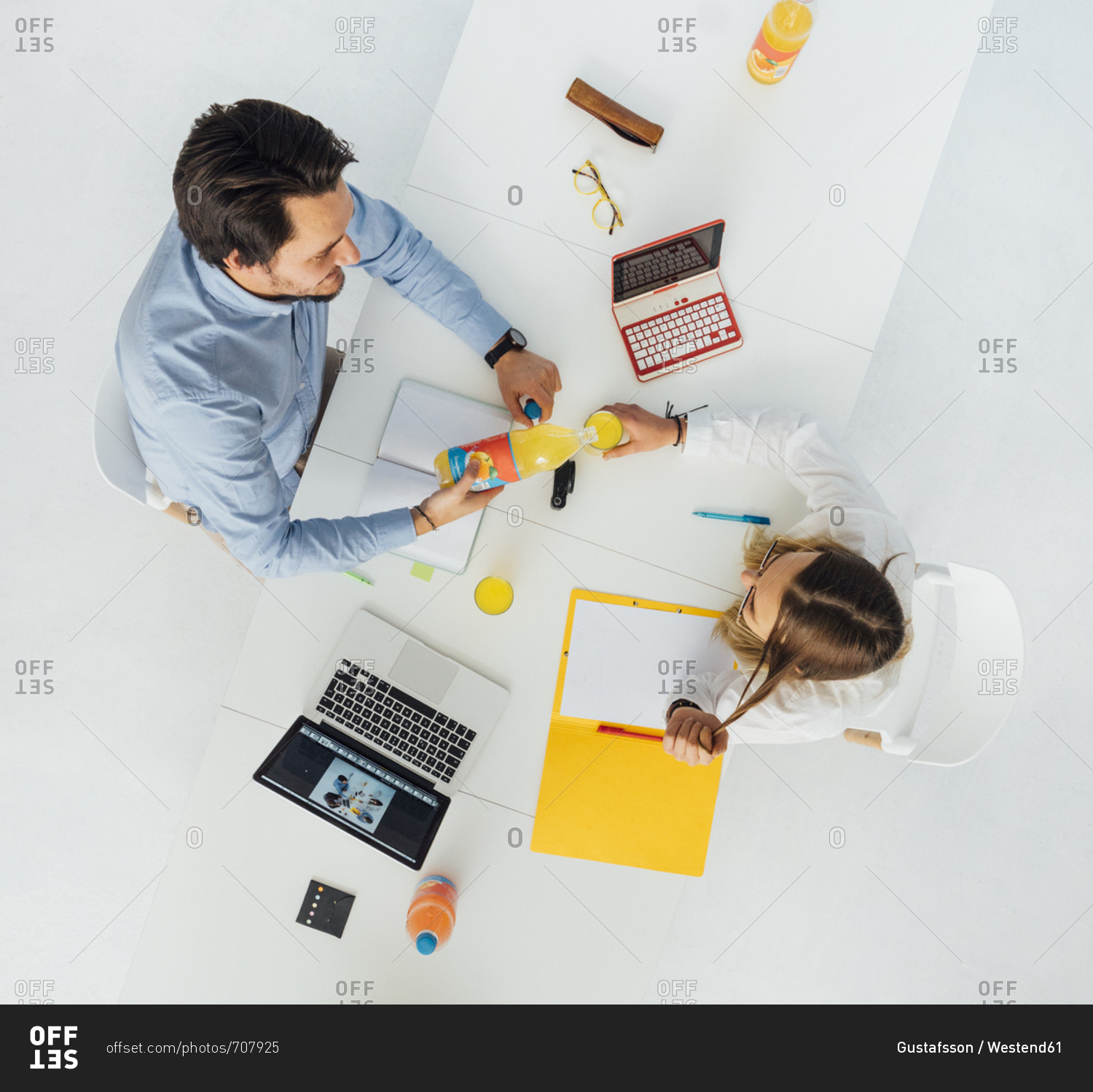 Two business people at meeting table in office- top view