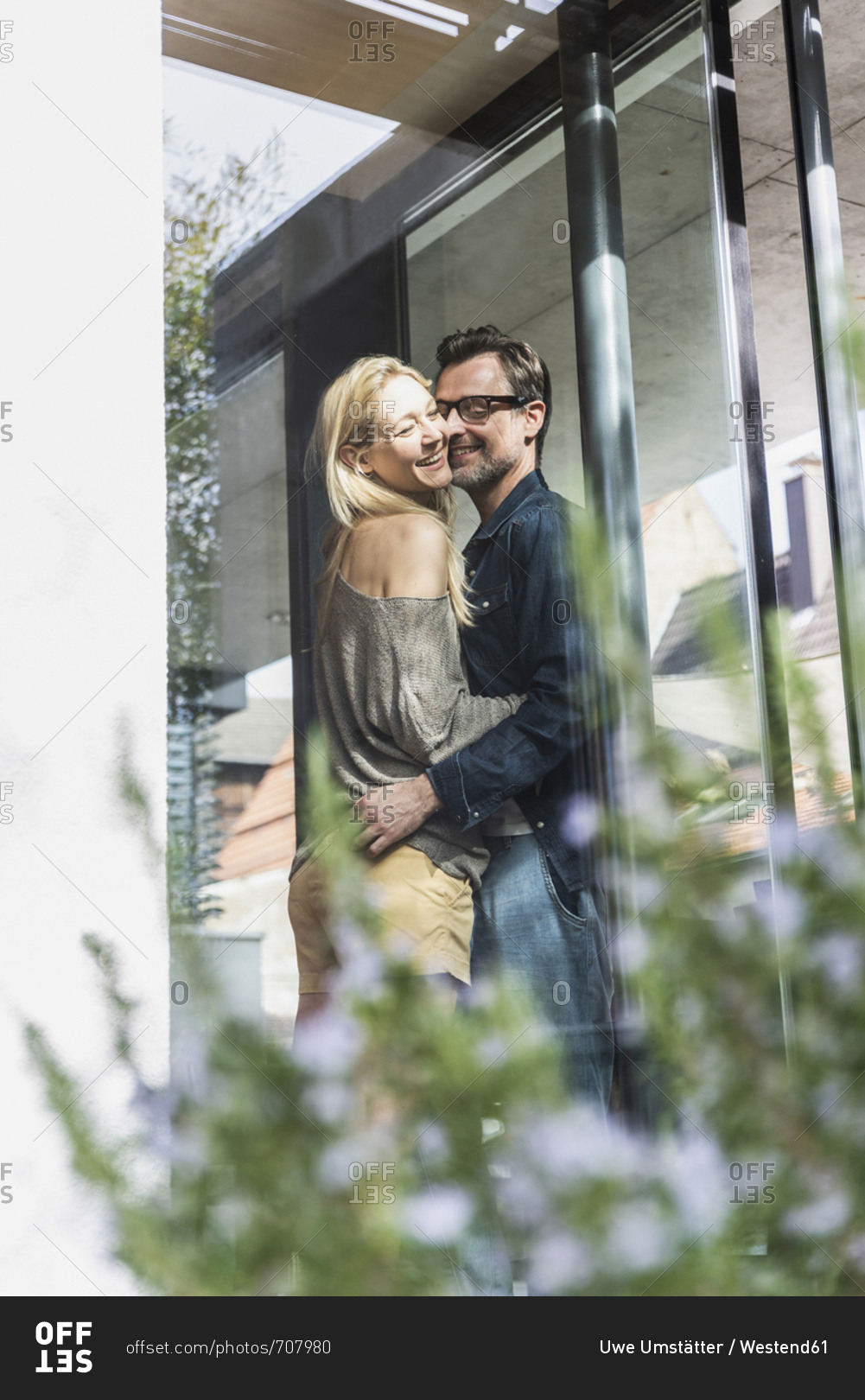 Happy mature couple standing on terrace of their house