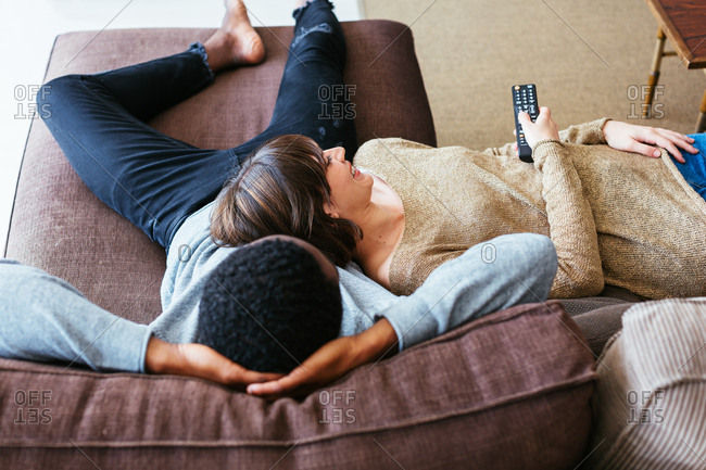 Happy Mixed Race Couple Relax On Couch In Living Room Watch Movie