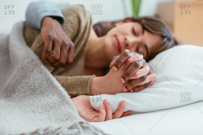 Young couple holding hands sleeping on bed