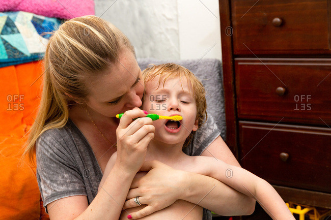 Mother attempting to brush her toddler son's teeth before going to bed