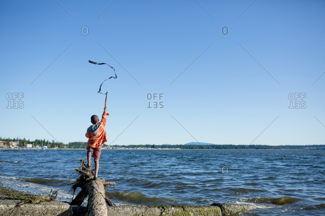 Boy waving a streamer on a stick on a windy day at the beach