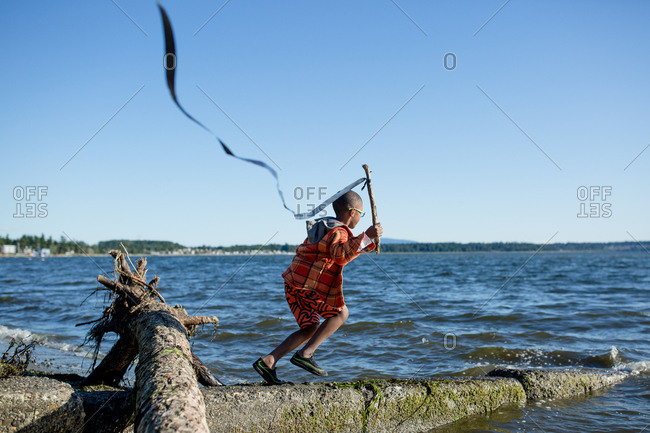 Boy running with streamer on a stick at the coast
