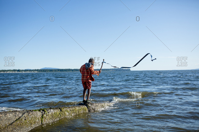 Boy holding streamer on a stick at the coast