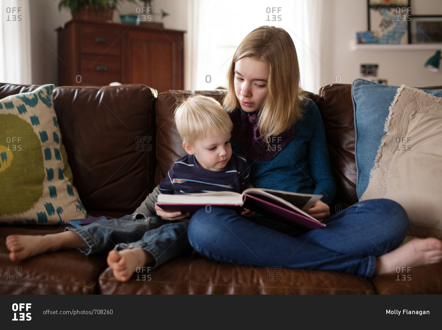Young girl reading story to little brother on couch