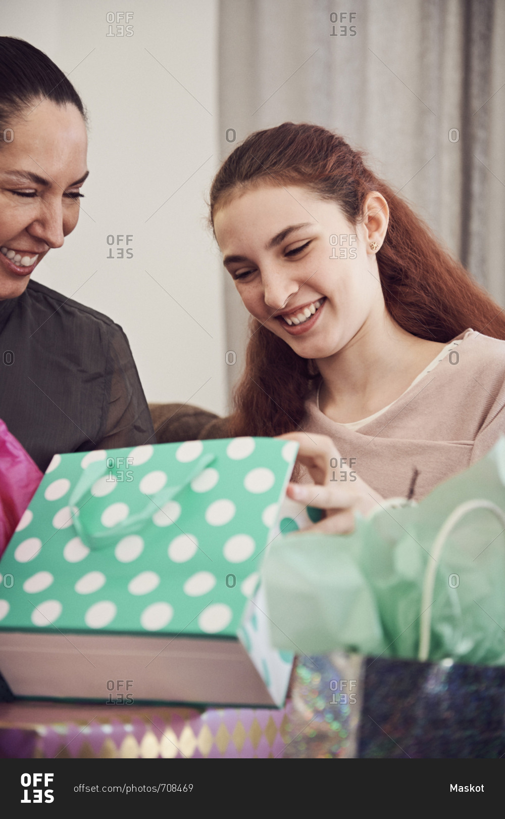 Excited girl looking at birthday present while sitting with mother at home