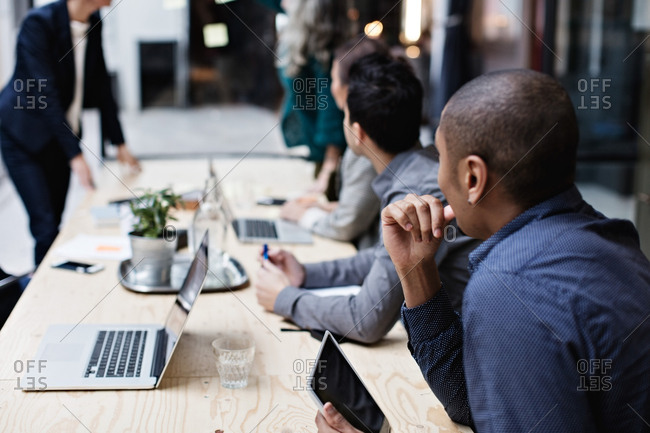 Business colleagues listening while sitting at table during meeting