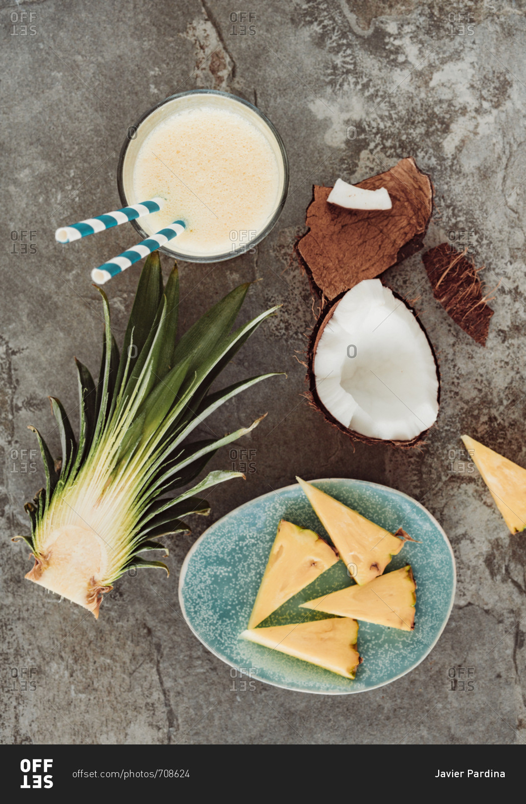 Overhead view of coconut and pineapple smoothie surrounded by pineapple chunks and coconut