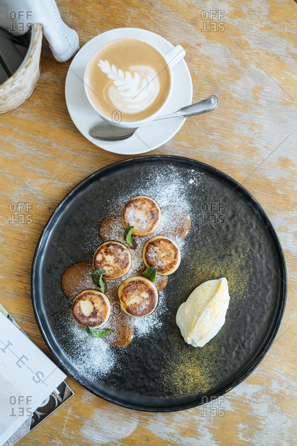 Overhead view of fried custard with caramel sauce served with a latte