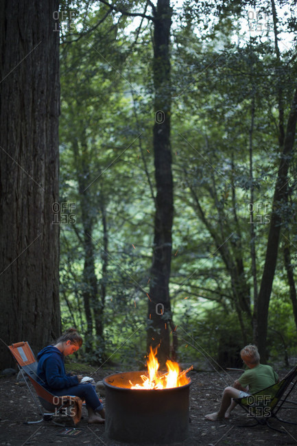 Two kids hanging out by the campfire at a campground