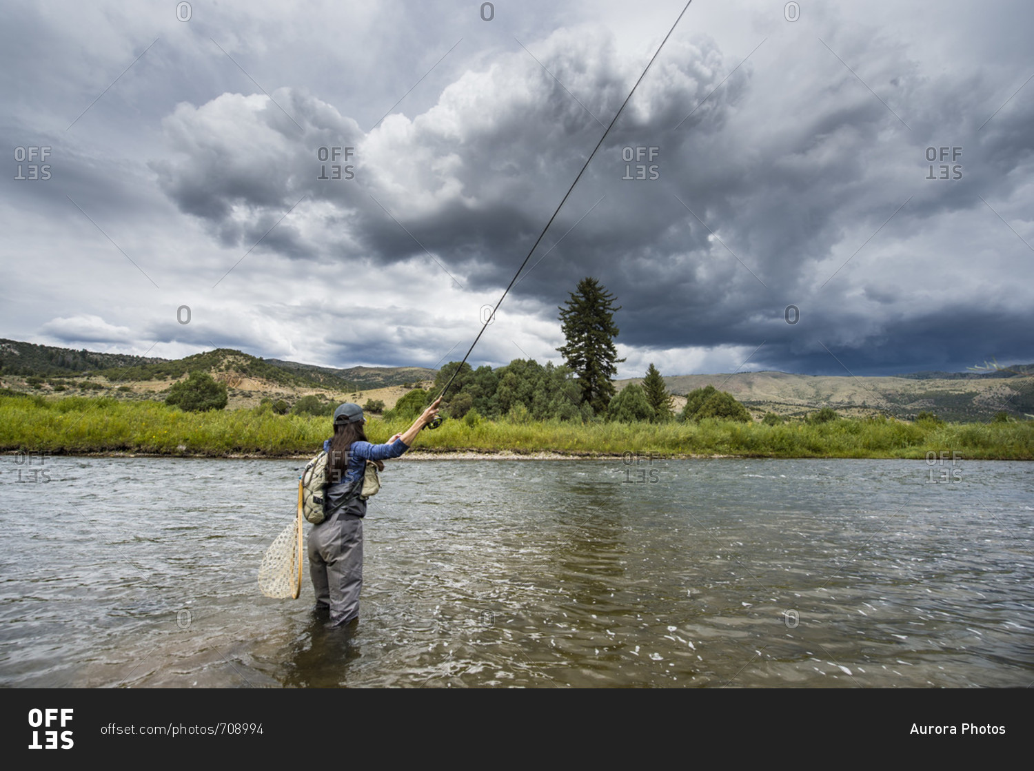 Clouds over women fishing in river, Colorado, USA