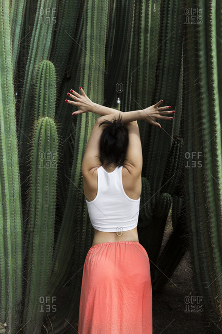 Back view of young brunette posing surrounded by cactus