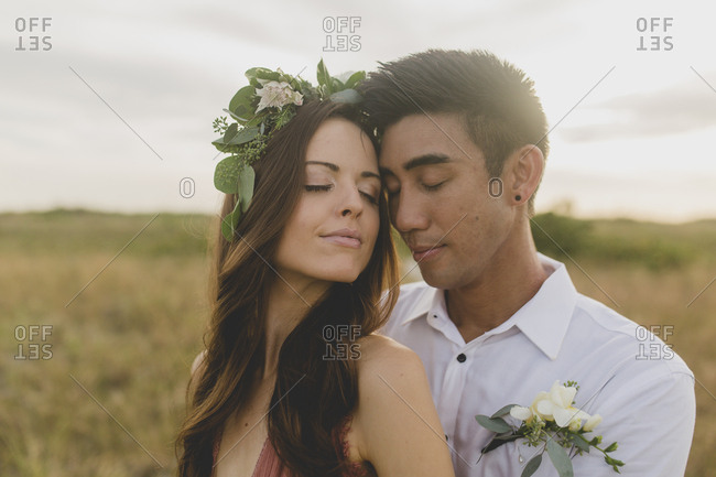 A couple in a field snuggle in with each other forehead to forehead