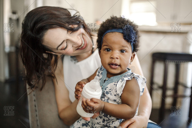 Close-up of happy mother with daughter sitting on chair at home