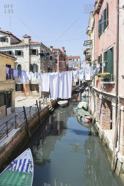 Laundry hanging over boat-lined canal of Venice, Italy