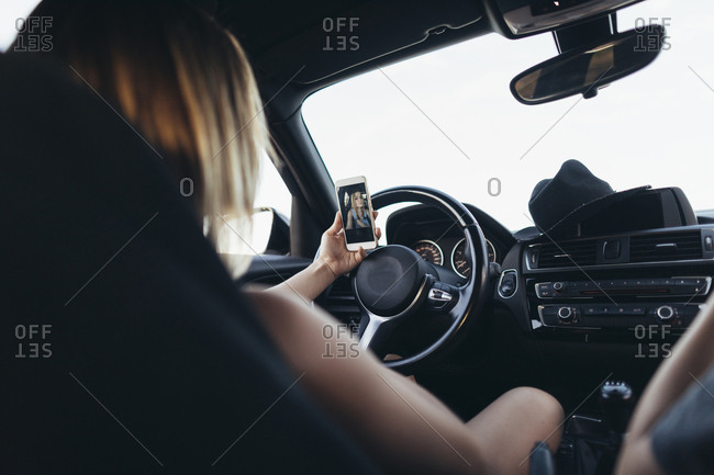 Young woman taking selfie in her car stock photo - OFFSET