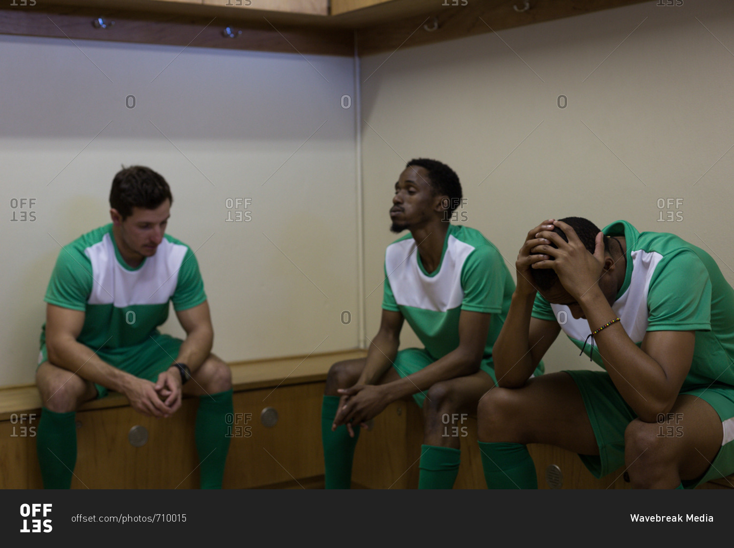 Tense football players sitting on dressing room