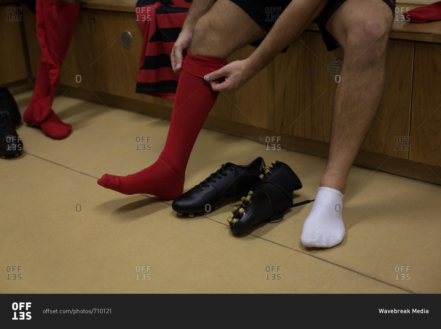 Low section of football player wearing socks in dressing room