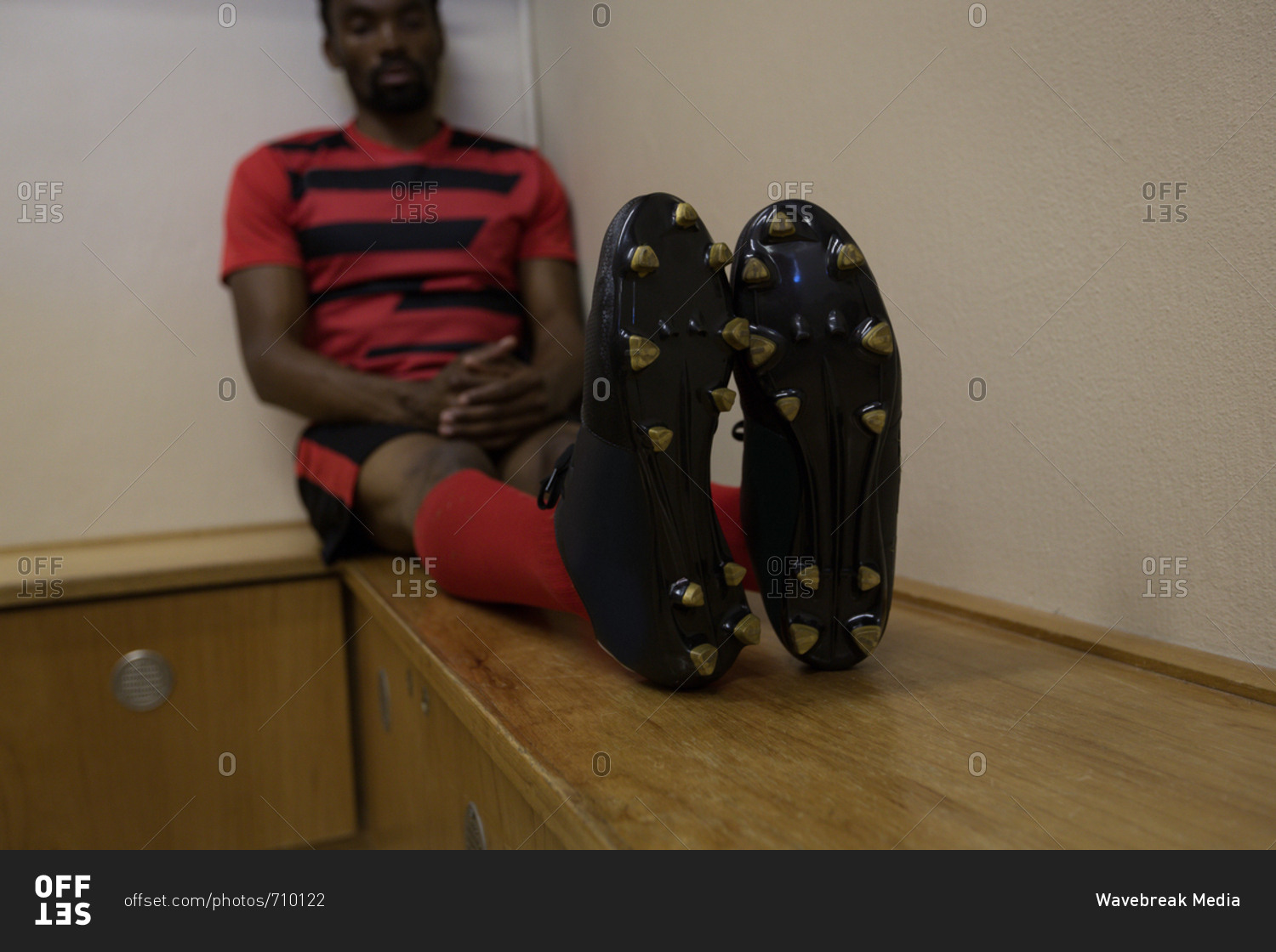 Football player relaxing on bench in dressing room