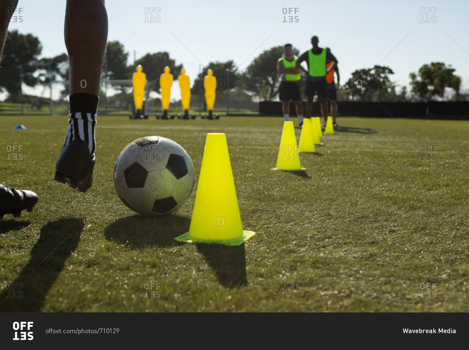 Soccer player dribbling the ball through cones in sports field