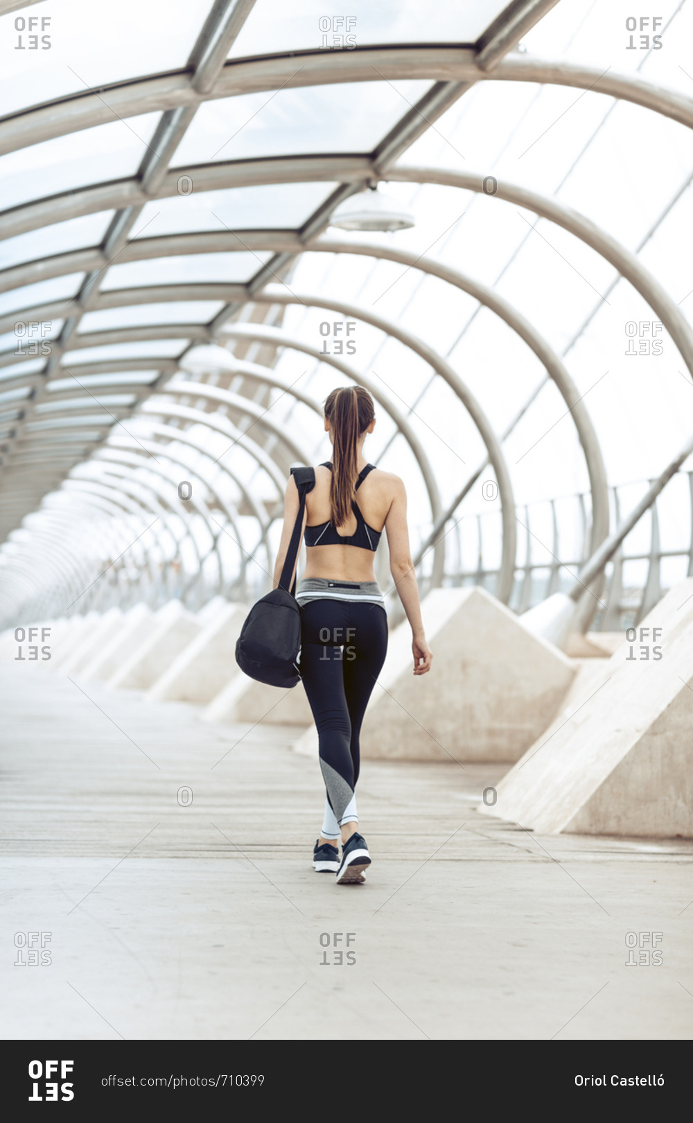 Rearview of athletic woman in sportswear carrying gym bag heading to workout