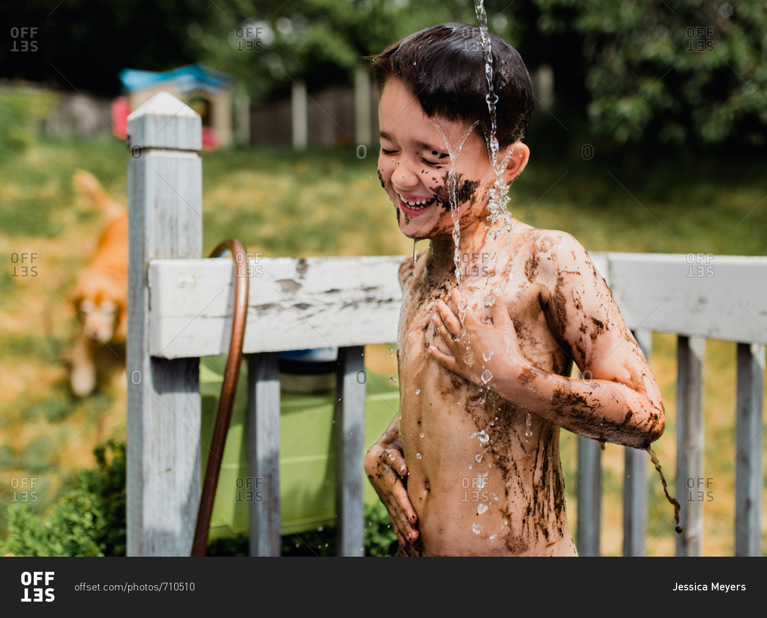 Muddy boy cleaning off on the back porch stock photo OFFSET