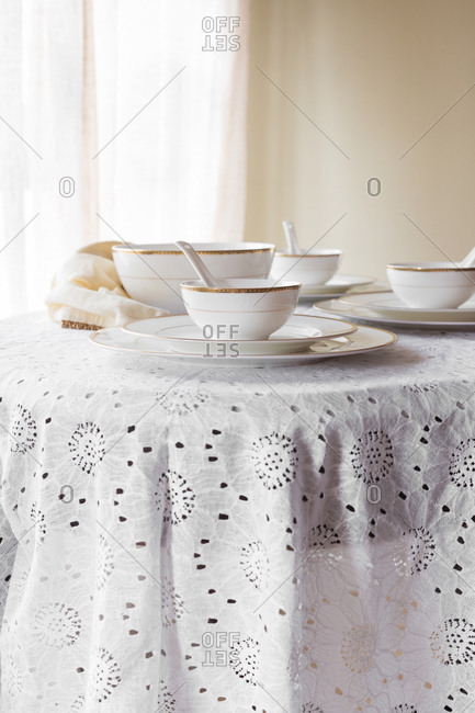 White with golden rim bone china with white and gold napkin on a white lace tablecloth